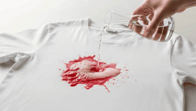 Frischer Rotweinfleck auf einem weißen T-Shirt wird mit Weißwein oder Mineralwasser zur Vorbehandlung begossen.