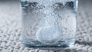 Sich aufl&ouml;sende Aspirin-Tablette im Wasserglas als Hausmittel gegen Blutflecken auf dem Teppich.