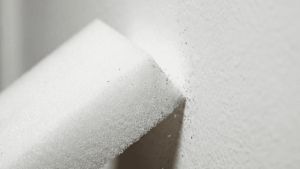 Nahaufnahme eines wei&szlig;en Zauberradierser-Schwamms bei der Fleckenentfernung auf einer Wand.