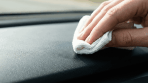 Eine Hand tupft vorsichtig mit einem wei&szlig;en, nebelfeuchten Mikrofasertuch Blut von einer schwarzen Lederfl&auml;che ab.