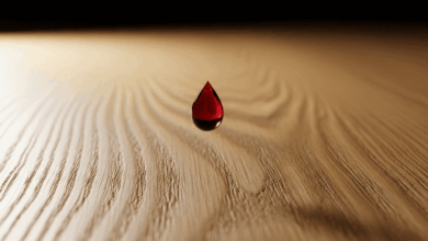 Rotweinflecken auf Holz entfernen: Ein Tropfen Rotwein fällt auf einen hellen Eichentisch.