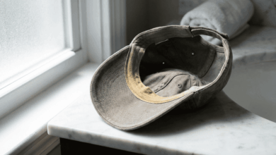 Basecap mit sichtbarem gelbem Schweißrand am Stirnband liegt umgedreht auf einer Marmorablage – typischer Schweißfleck an einer Kappe