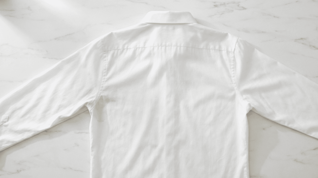 Sauberes wei&szlig;es Hemd ohne Schwei&szlig;flecken liegt ausgebreitet auf einer Marmoroberfl&auml;che &ndash; Ergebnis nach erfolgreicher Fleckenbehandlung